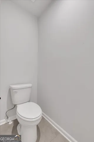a white toilet sitting next to a white wall