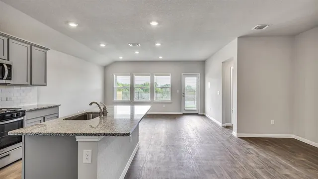a kitchen with granite countertop a sink and a stove top oven