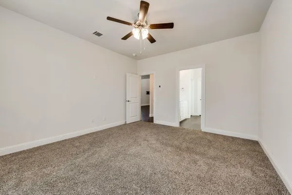 an empty room with windows and ceiling fan