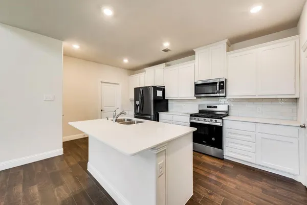 a kitchen that has a sink and a stove with wooden floor