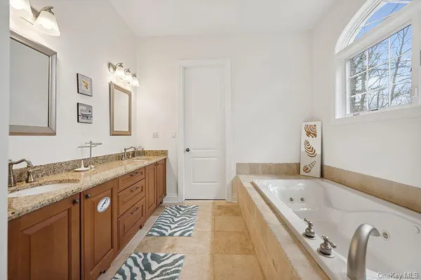 a bathroom with a granite countertop tub sink and mirror