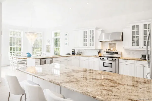 a large kitchen with granite countertop a stove a sink and white cabinets