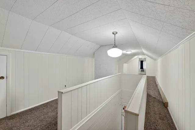 a view of a hallway with wooden floor and chandelier