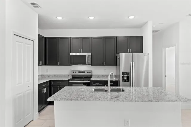 a kitchen with stainless steel appliances granite countertop a sink and a refrigerator