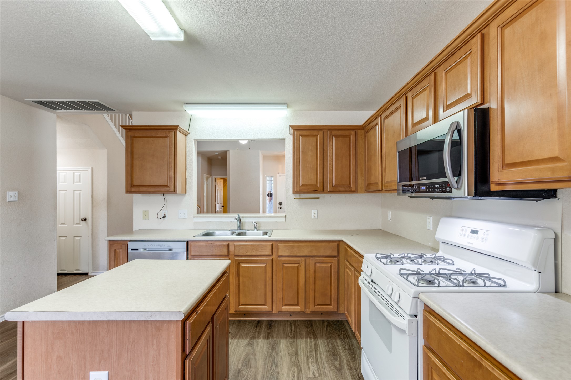 5043 Hartson Kyle, TX 78640 - Photo 11 of 30 Kitchen with stainless steel appliances, light wood-style flooring, light countertops, wood finish cabinets, and a textured ceiling