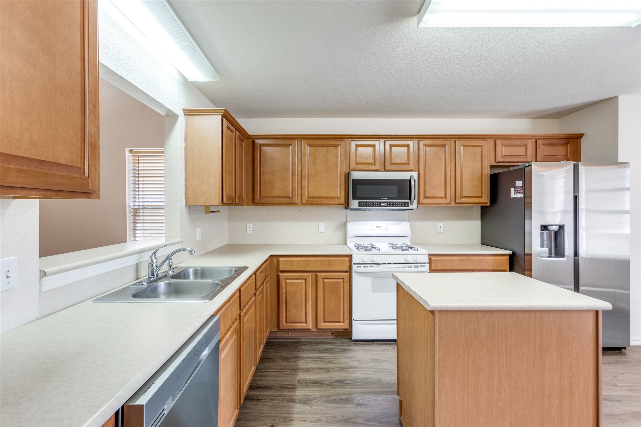 5043 Hartson Kyle, TX 78640 - Photo 12 of 30 Kitchen featuring stainless steel appliances, light countertops, a center island, dark wood-type flooring, and wood finish cabinets