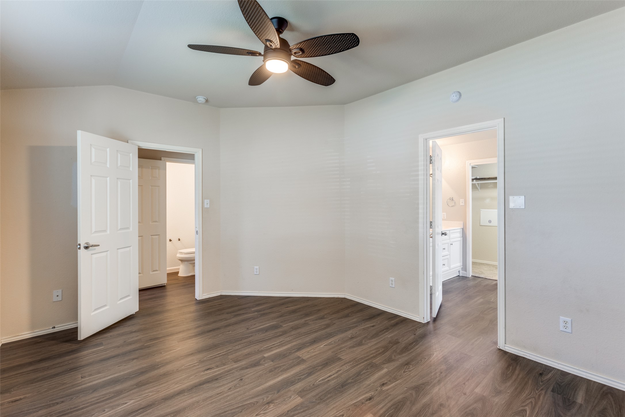 5043 Hartson Kyle, TX 78640 - Photo 14 of 30 Unfurnished bedroom with ensuite bath, lofted ceiling, dark wood-type flooring, and a ceiling fan