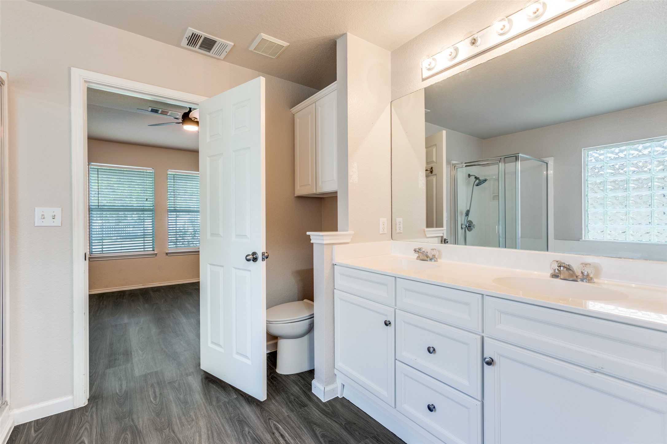 5043 Hartson Kyle, TX 78640 - Photo 16 of 30 Bathroom featuring double vanity, a shower stall, dark wood-style floors, and a ceiling fan
