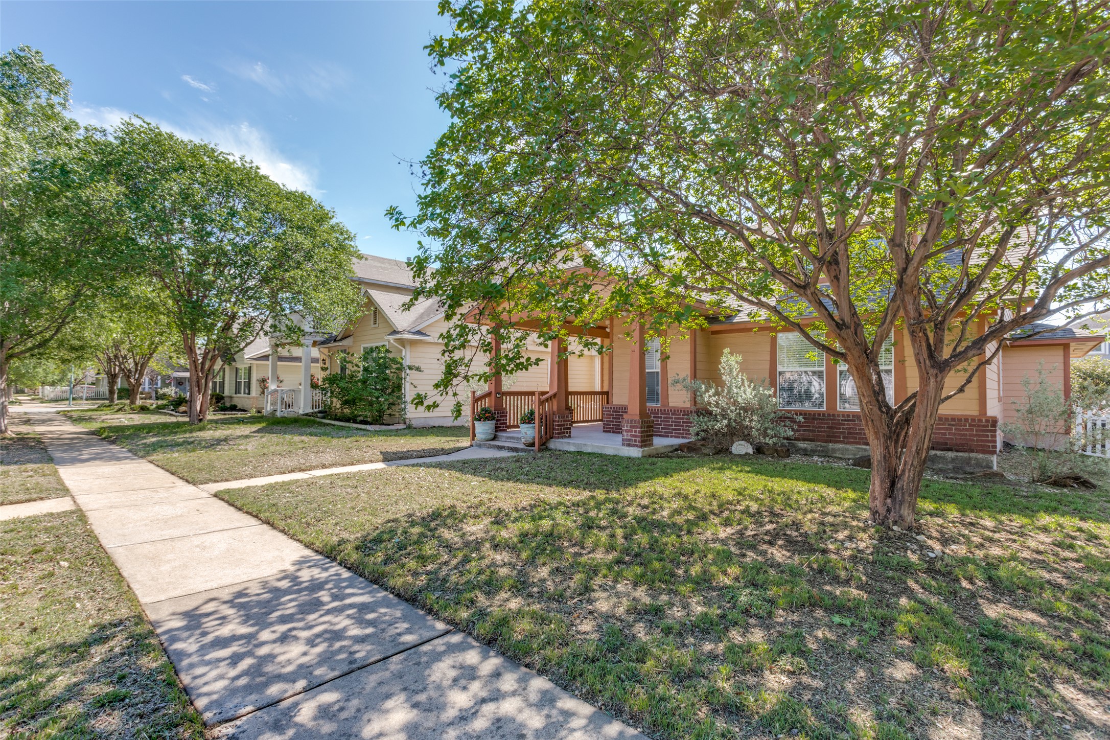 5043 Hartson Kyle, TX 78640 - Photo 2 of 30 View of property hidden behind natural elements featuring brick siding, a front lawn, and a porch