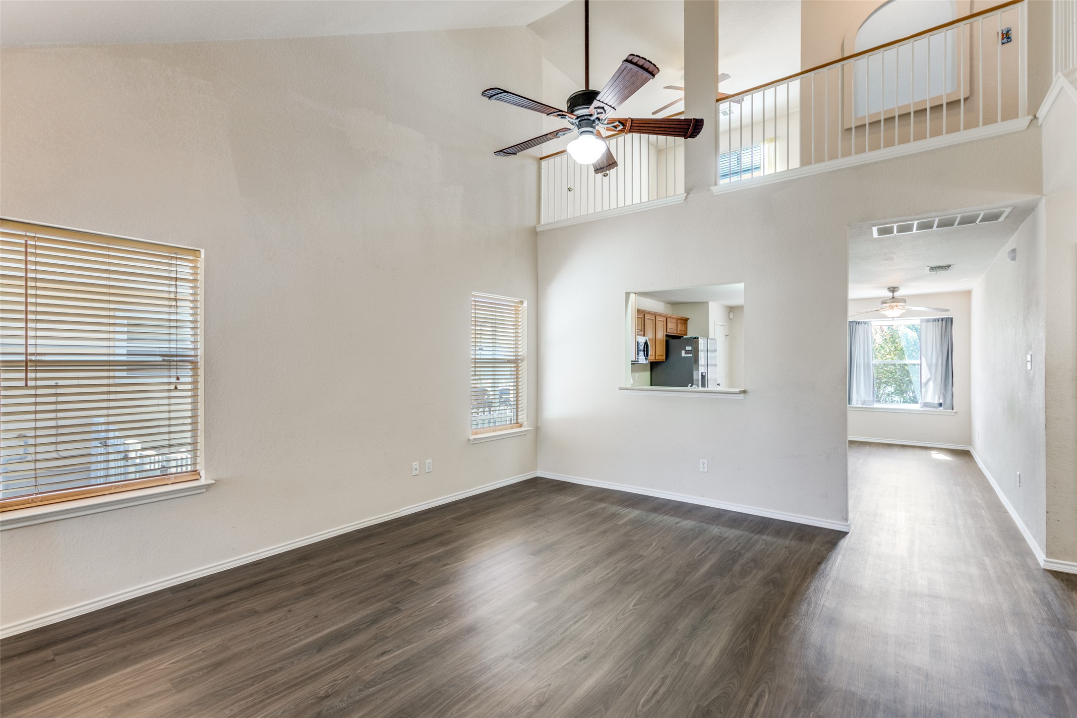 5043 Hartson Kyle, TX 78640 - Photo 4 of 30 Living room with ceiling fan, an open ceiling to the second floor, and dark wood-style finished floors
