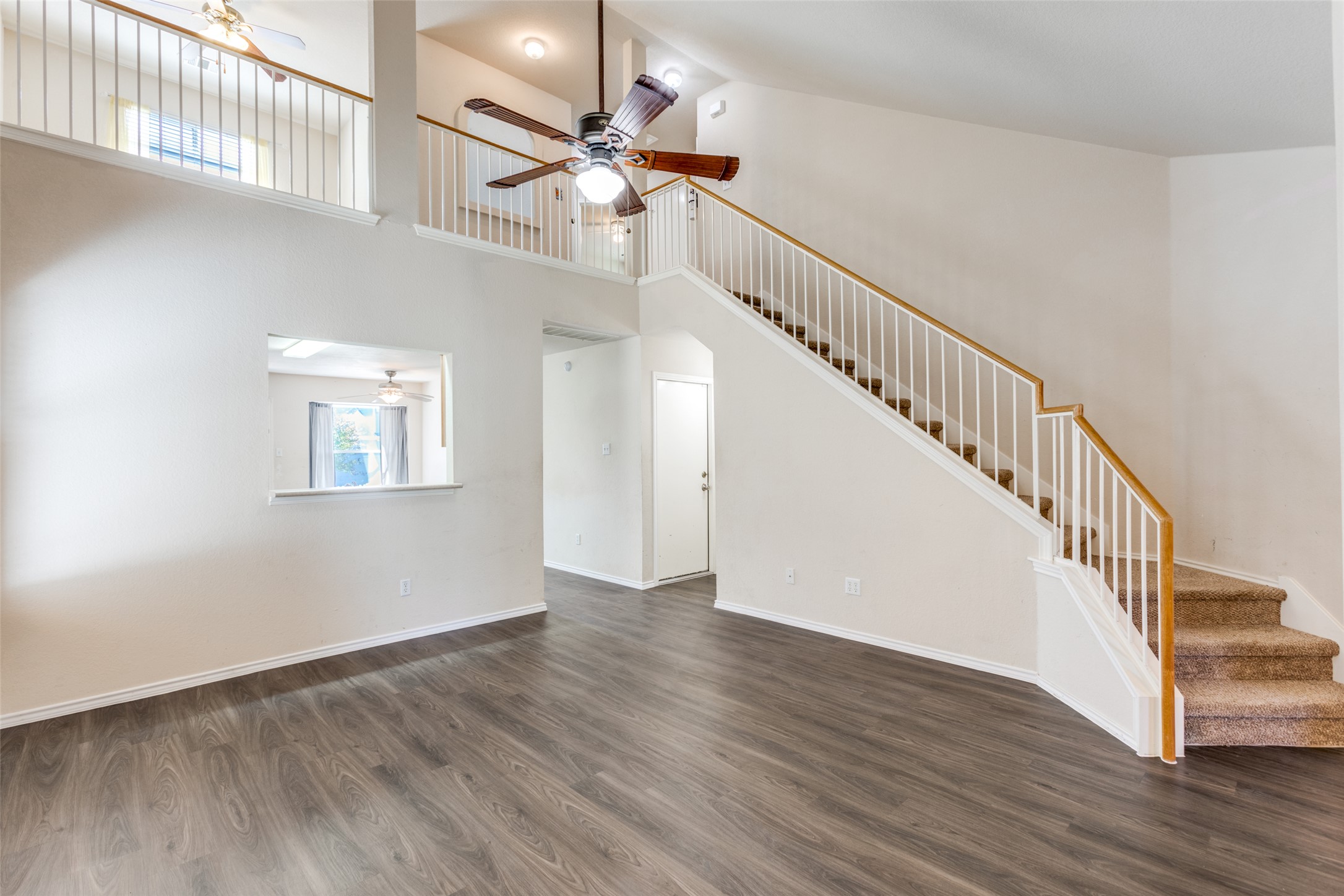 5043 Hartson Kyle, TX 78640 - Photo 5 of 30 Unfurnished living room with ceiling fan, dark wood-style floors, and , an open ceiling to the second floor.