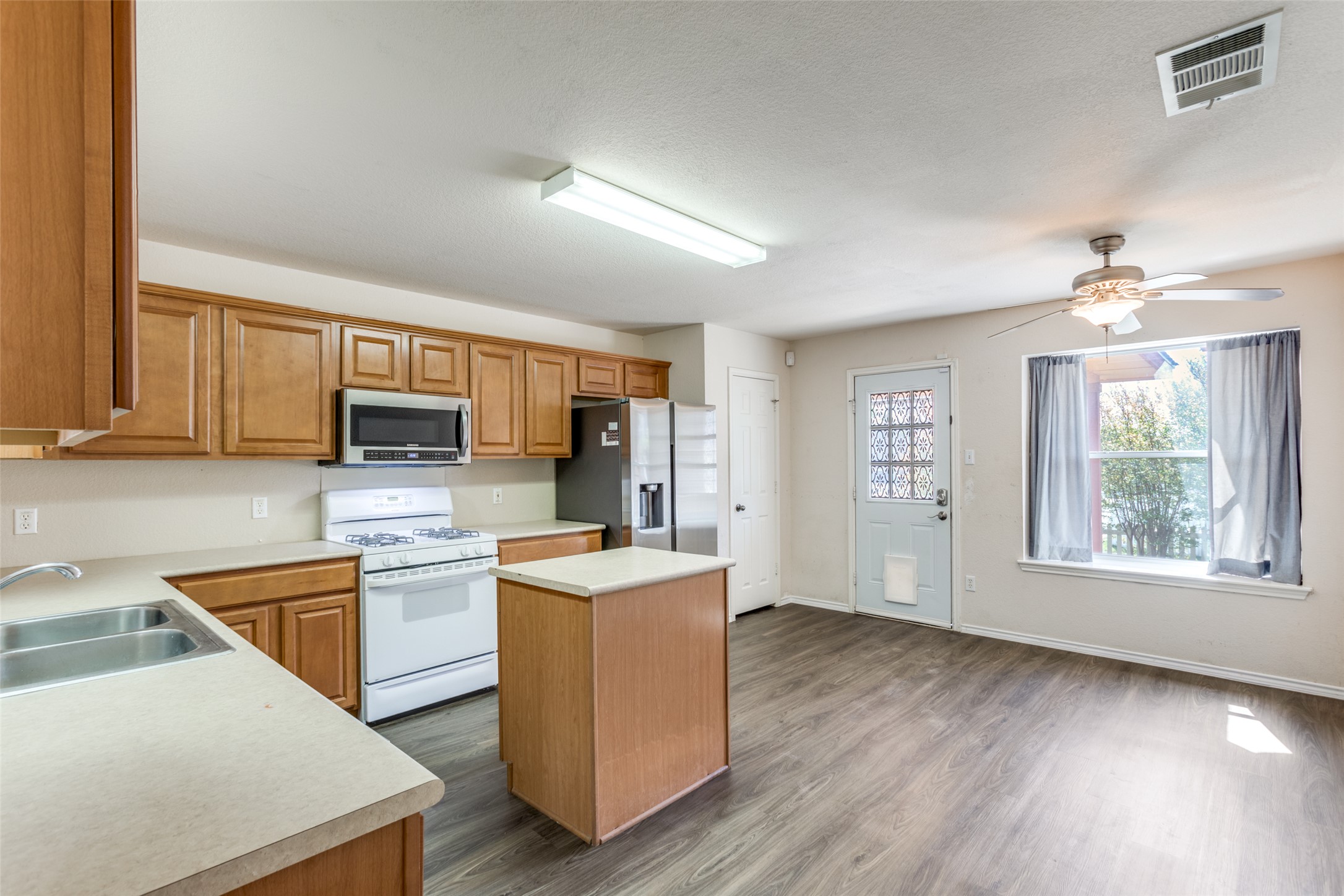 5043 Hartson Kyle, TX 78640 - Photo 8 of 30 Kitchen featuring a center island, stainless steel appliances, wood finish cabinets, and light countertops