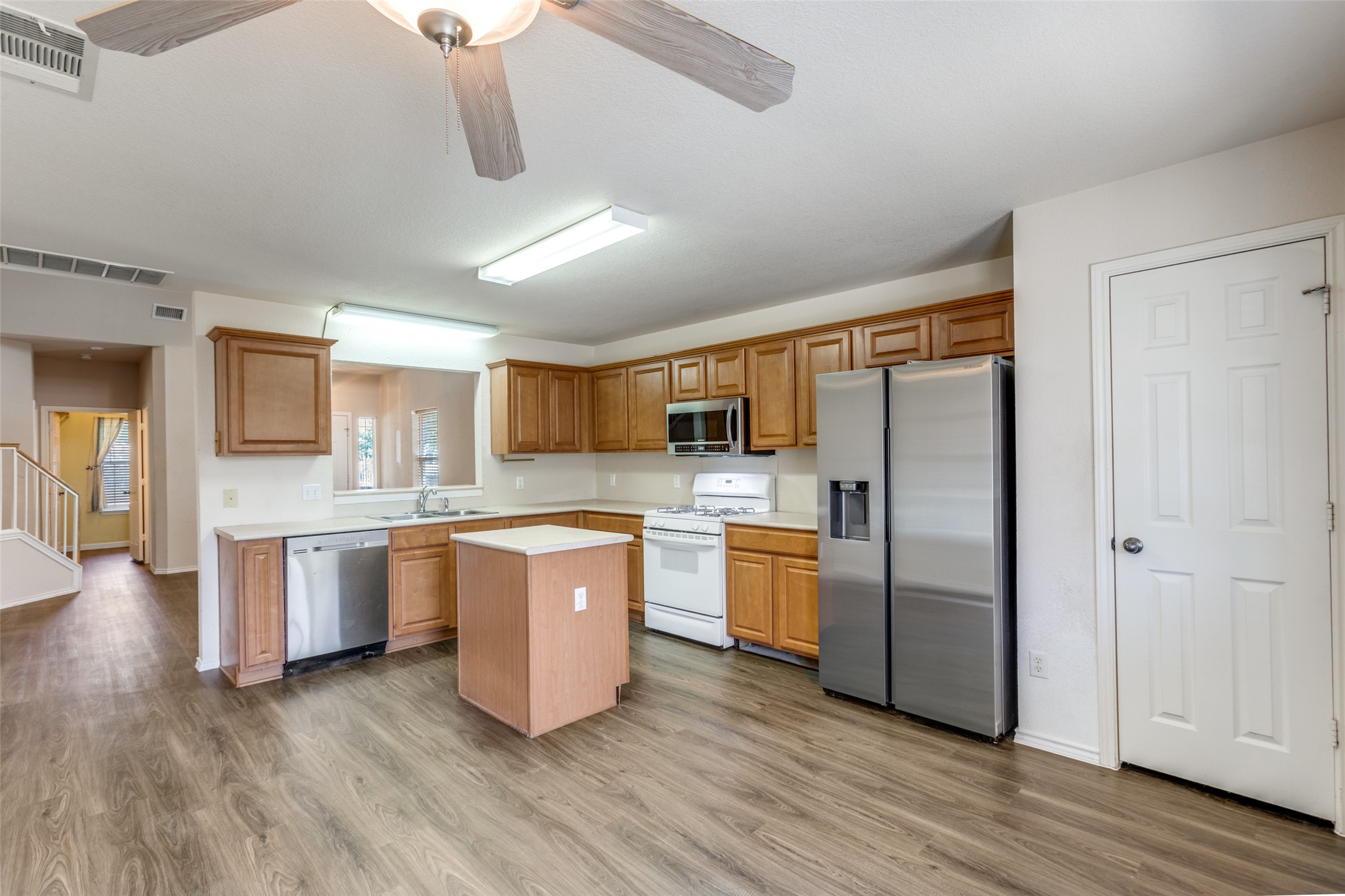 5043 Hartson Kyle, TX 78640 - Photo 10 of 30 Kitchen and Dining featuring a ceiling fan, stainless steel appliances, light countertops, wood finish cabinets, and dark wood finished floors