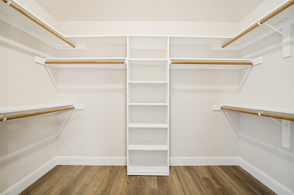 3020 Ridge Hollow Drive Plano, TX 75023 - Photo 25 of 28 Built-in closet system featuring natural wood-finish hanging rods, white shelving, and wood-finish flooring