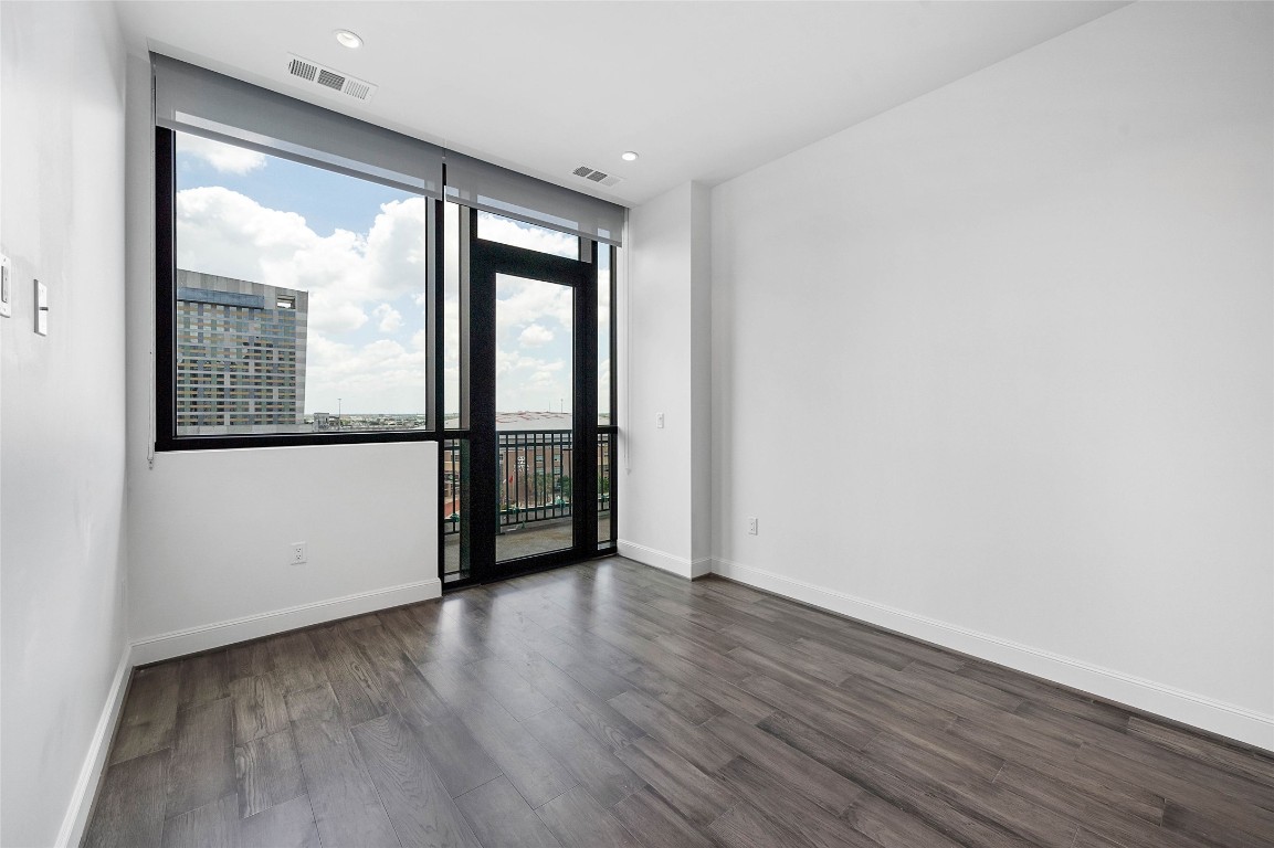 1211 Caroline Street, Unit 1102 Houston, TX 77002 - Photo 6 of 9 an empty room with wooden floor and windows