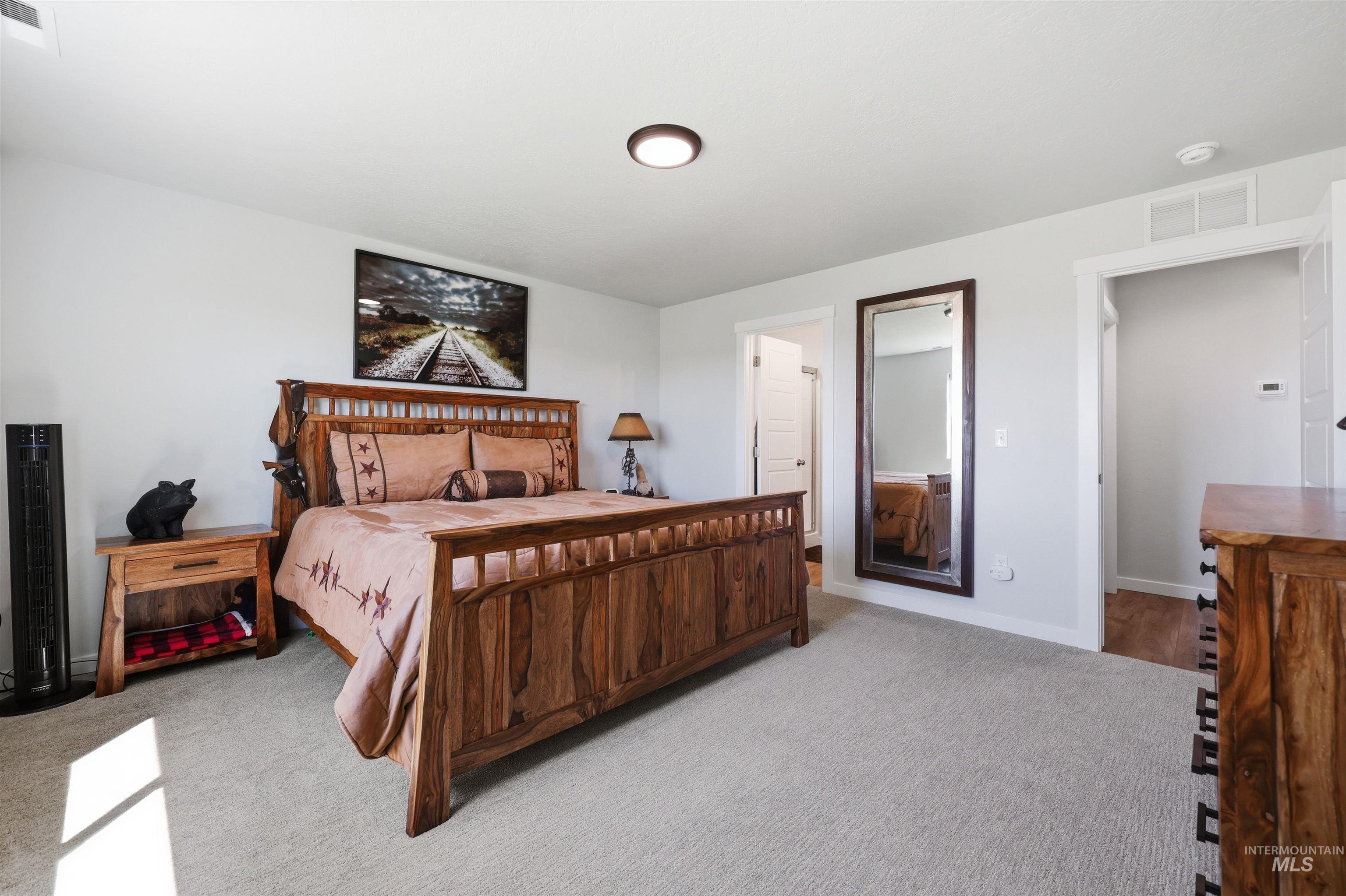 3811 West Maypearl Street Meridian, ID 83642 - Photo 24 of 39 Carpeted bedroom with a built-in ceiling light fixture, two open doorways, and a full-length wall mirror