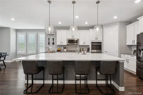 a kitchen with stainless steel appliances a dining table chairs stove and white cabinets