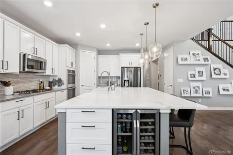 a large kitchen with kitchen island a stove a sink a dining table and chairs with wooden floor