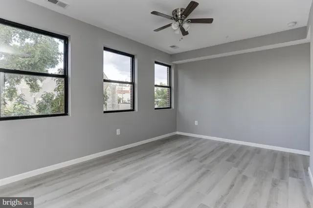 a view of an empty room with a window and wooden floor