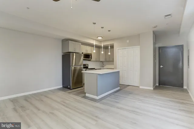 a kitchen with stainless steel appliances kitchen island granite countertop a refrigerator and a sink