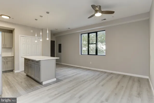 a living room with stainless steel appliances kitchen island hardwood floor and ceiling fan