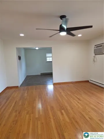 an empty room with wooden floor fan and windows