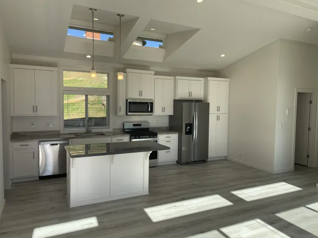 a kitchen with stainless steel appliances kitchen island granite countertop a refrigerator a stove top oven a sink and dishwasher