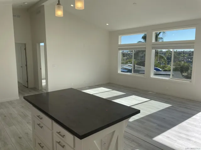 an open kitchen with granite countertop a sink and a black white cabinets