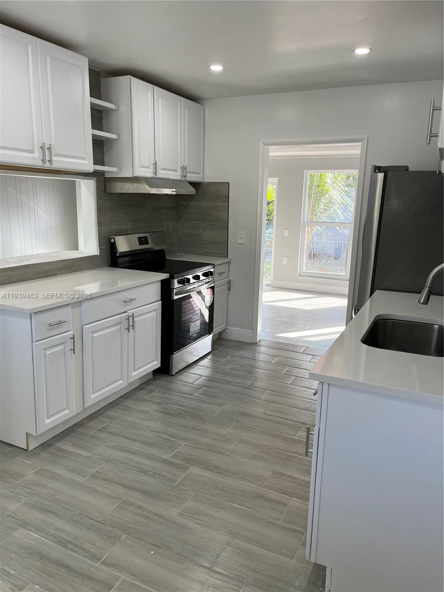 1386 Northwest 38th Street, Unit 1 Miami, FL 33142 - Photo 4 of 6 a kitchen with stainless steel appliances granite countertop a sink a stove and a refrigerator