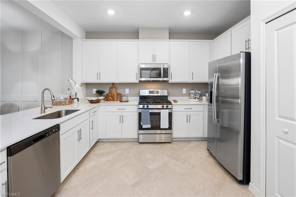 14888 Anchorage Road Punta Gorda, FL 33982 - Photo 9 of 34 Kitchen with appliances with stainless steel finishes, light countertops, white cabinets, light tile patterned floors, and recessed lighting