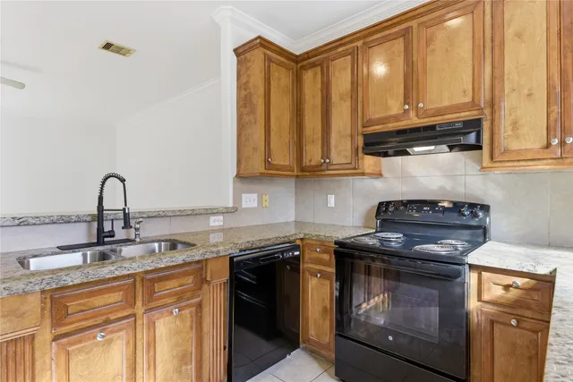 a kitchen with granite countertop a stove top oven cabinetry a sink and dishwasher
