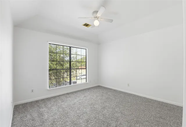 an empty room with windows and ceiling fan