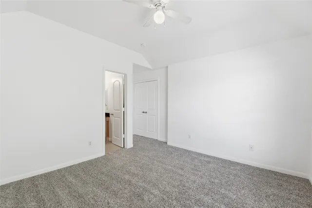 an empty room with a ceiling fan and carpet
