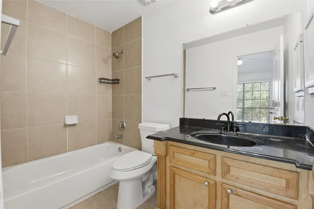 a bathroom with a granite countertop sink a toilet a mirror a bathtub and shower
