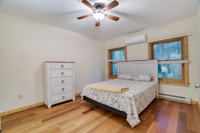 a bedroom with a bed and a dresser with wooden floor