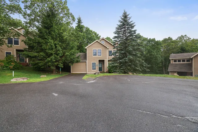 a view of a house with a yard and large tree