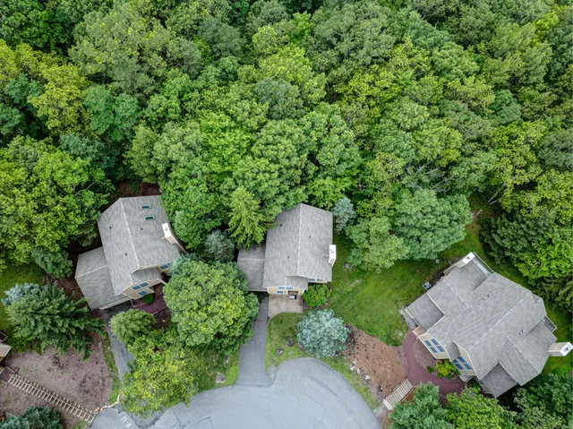 an aerial view of residential house with outdoor space and trees all around