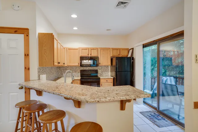 a kitchen with granite countertop kitchen island stainless steel appliances a refrigerator and a sink