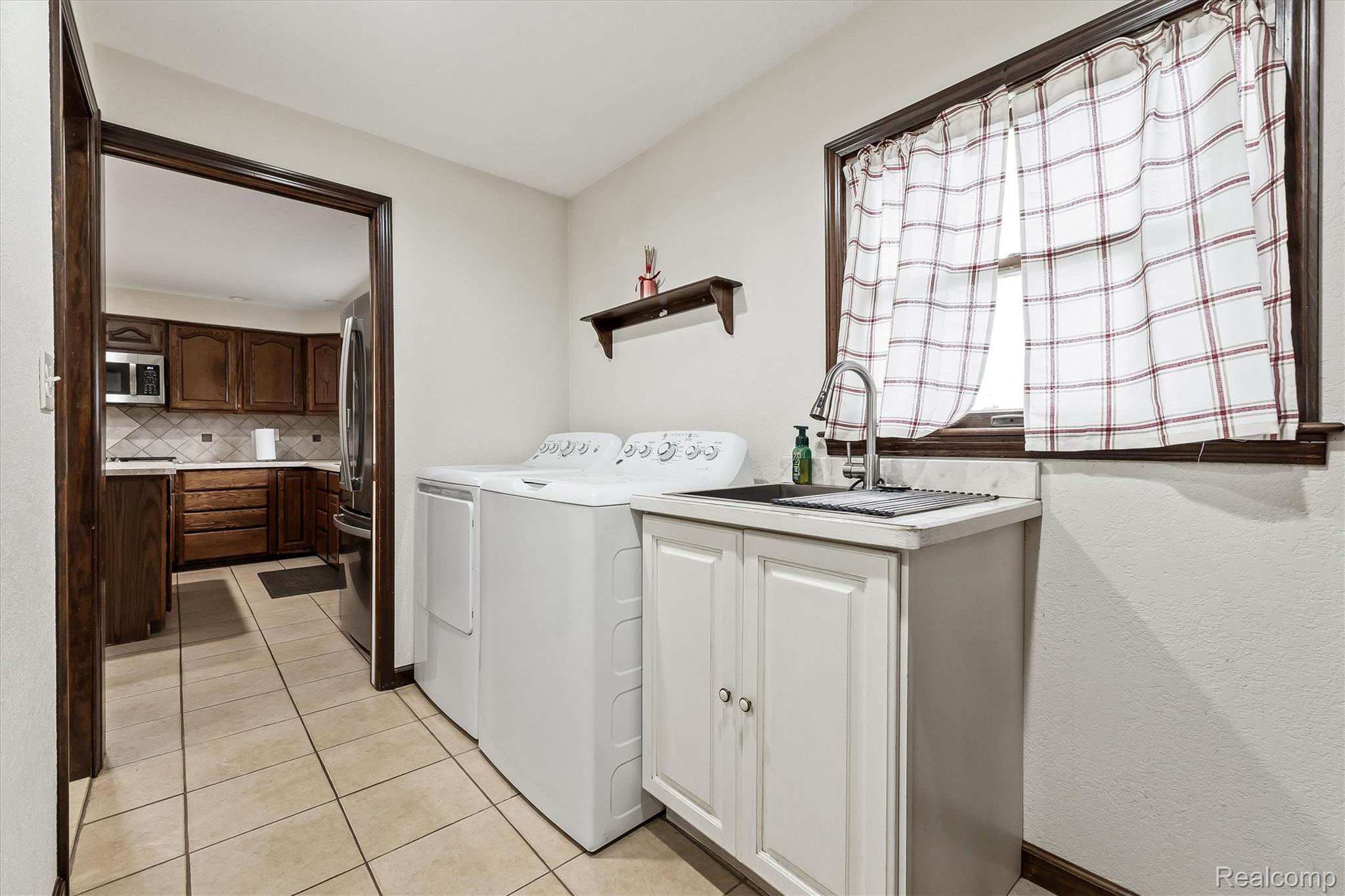 3553 North State Road Owosso, MI 48867 - Photo 18 of 45 Tiled flooring, utility sink with base cabinetry, window with dark trim, and a built-in wall shelf