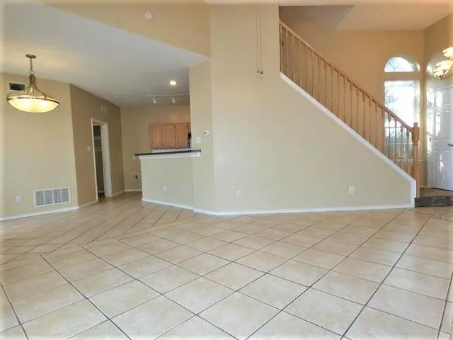 a view of an empty room and chandelier fan