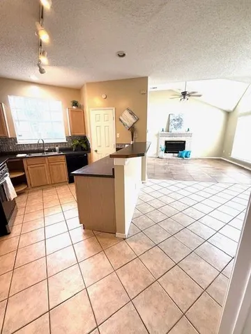 an empty room with a chandelier fan and windows