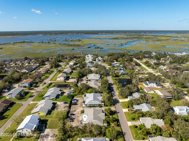 an aerial view of ocean and residential houses with outdoor space