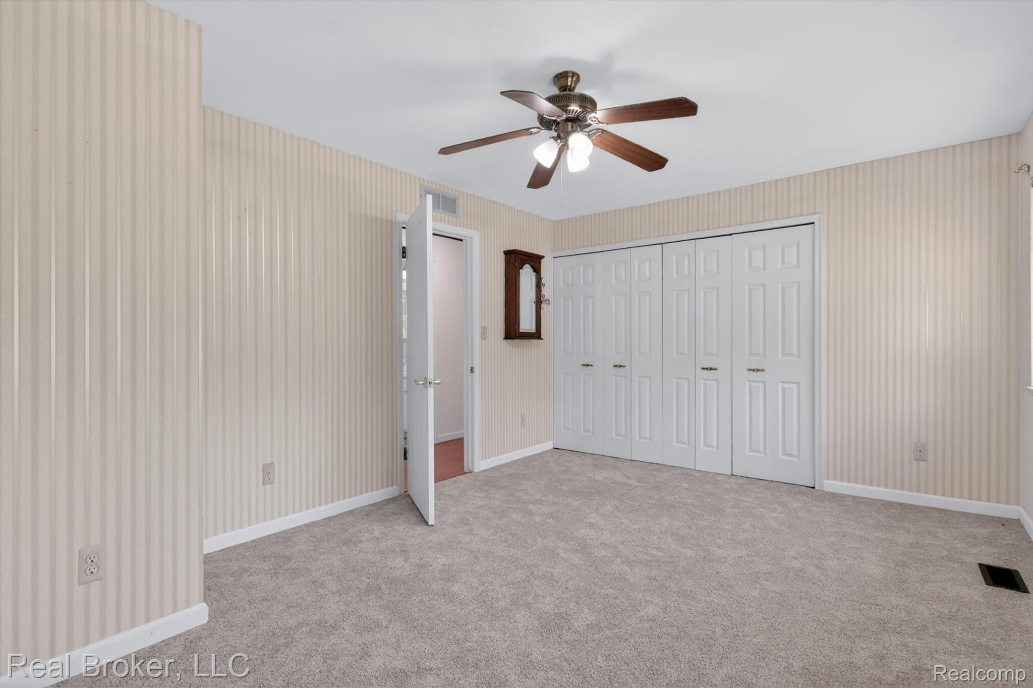 48050 Hull Road Belleville, MI 48111 - Photo 28 of 39 Carpeted room featuring a ceiling fan with light kit, vertical striped wallpaper, white bi-fold closet doors, and white trim