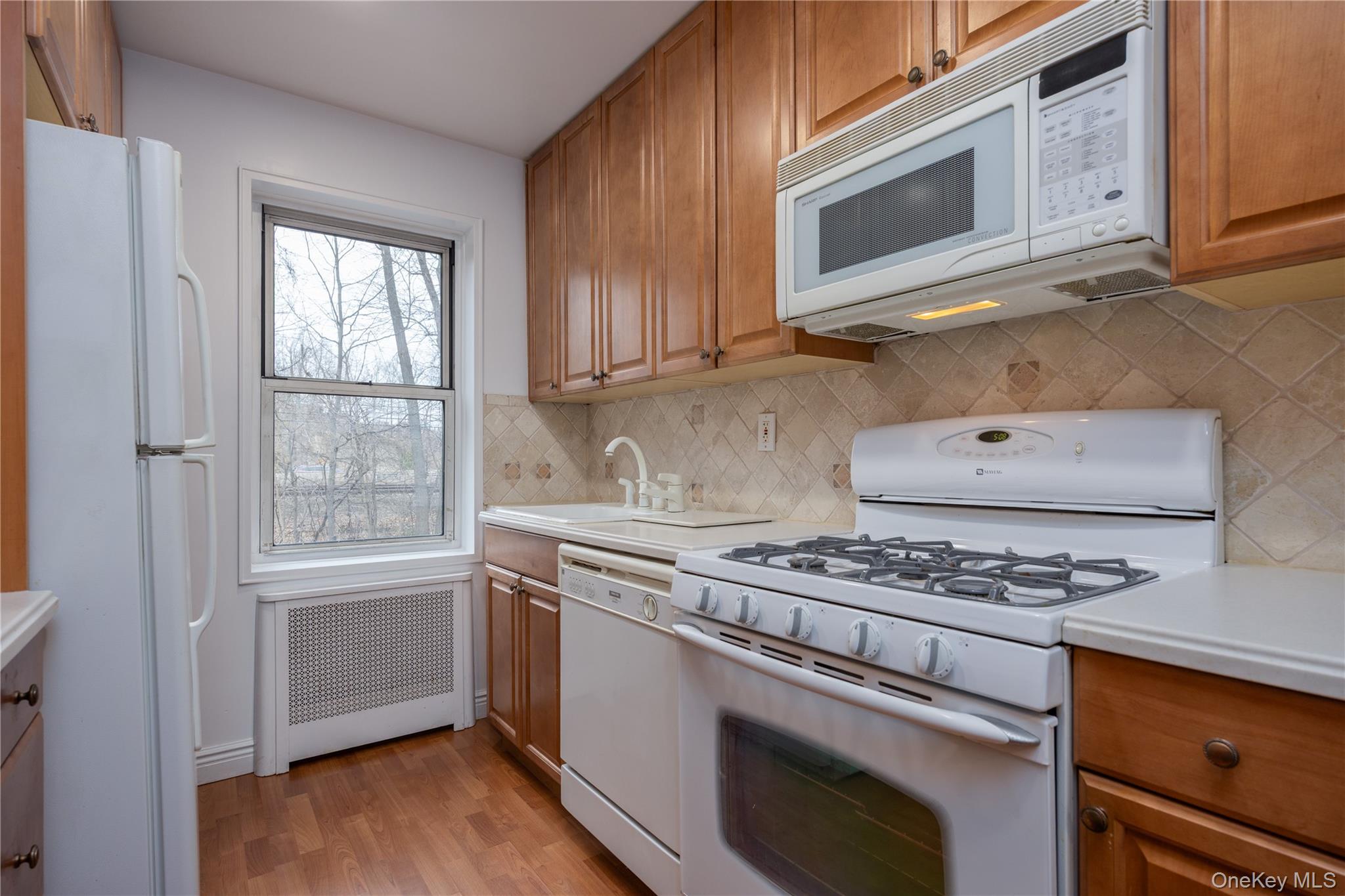 2303 Palmer Avenue, Unit F New Rochelle, NY 10801 - Photo 7 of 22 Kitchen with light countertops, a sink, radiator heating unit, brown cabinetry, and white appliances