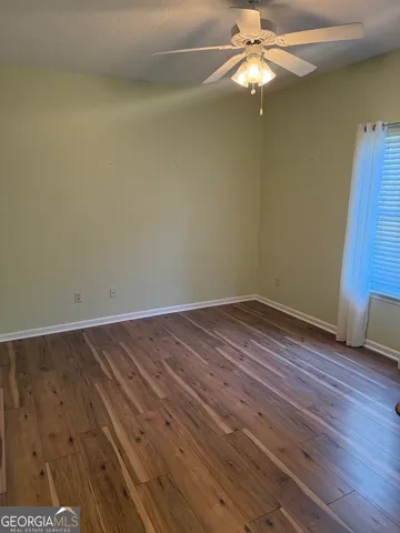 a view of a room with wooden floor a ceiling fan and staircase