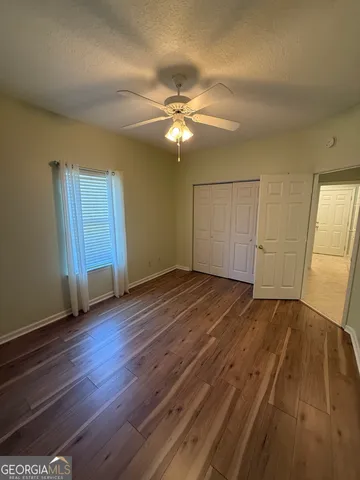 an empty room with wooden floor closet and windows