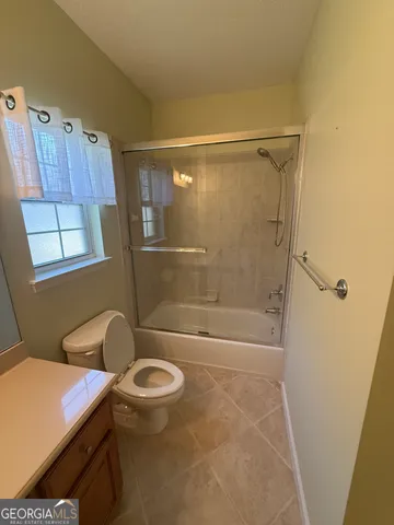 a bathroom with a granite countertop bathtub shower sink and toilet