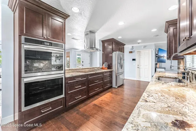 a kitchen with stainless steel appliances kitchen island granite countertop a refrigerator and a stove top oven
