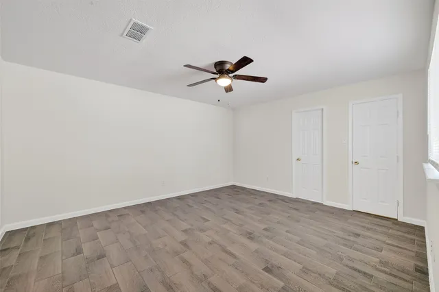 a view of empty room with wooden floor and fan