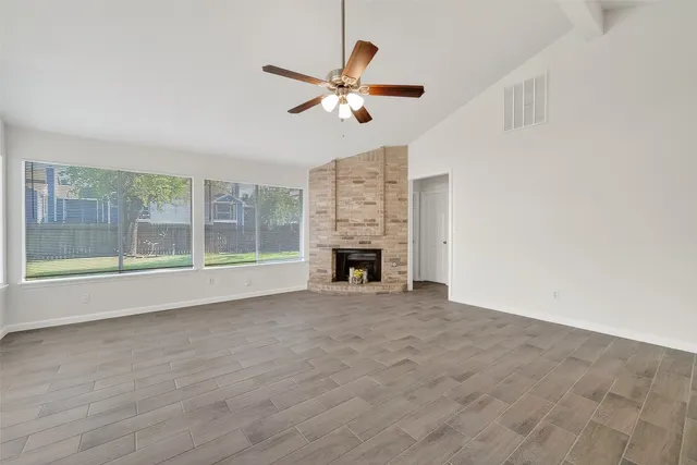 a view of an empty room with a fireplace and a window